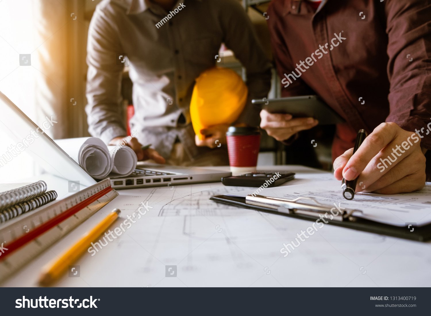 stock-photo-two-colleagues-discussing-data-working-and-tablet-laptop-with-on-on-architectural-project-at-1313400719